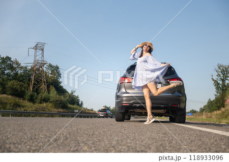 Cheerful Woman Posing by SUV on Sunny Day 118933096