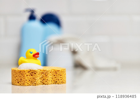 Yellow rubber duck, soap, bath foam on bath background, baby bath accessories Yellow rubber duck, soap, bath foam on bath background, baby bath accessories 118936485