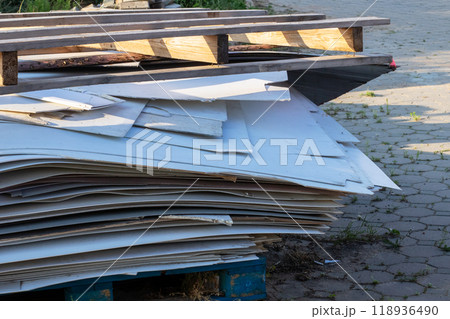 There is a stack of wooden pallets resting on the side of a road 118936490