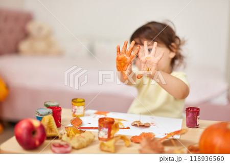 smiling little child girl painting hands and autumn leaves . baby showing hands in yellow paint smiling little child girl painting hands and autumn leaves . baby showing hands in yellow paint 118936560