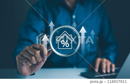 Real Estate Investment Concept. A businessman using a magnifying glass to examine a house icon with a percentage sign, representing real estate investment analysis and market trends. 118937911