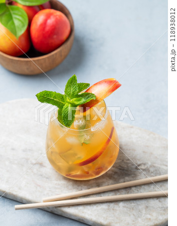Refreshing peach cocktail, lemonade or iced tea on a marble board with tube on a light background. 118938012