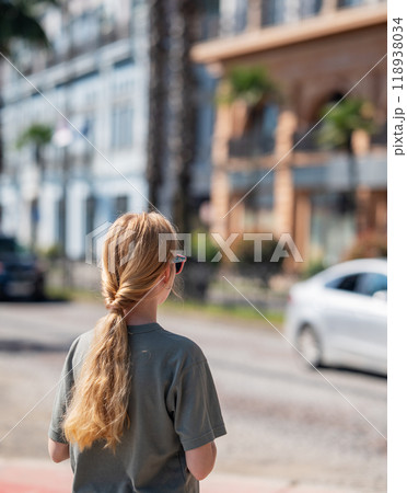 Young girl standing with back and looking at architectural building in city. 118938034