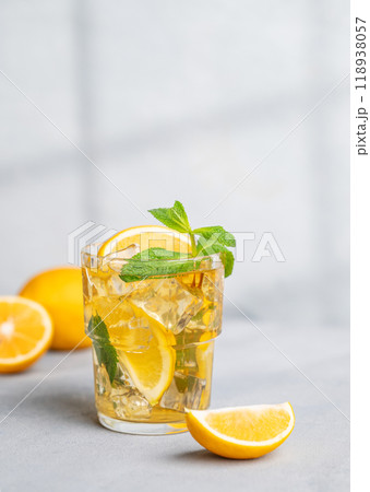 Iced tea with lemon, mint in a glass on light background with shadow and citrus fruits. 118938057
