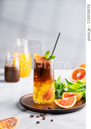 Coffee with orange juice (bumble) in a tall glass with ice and mint on a wooden plate Coffee with orange juice (bumble) in a tall glass with ice and mint on a wooden plate 118938058