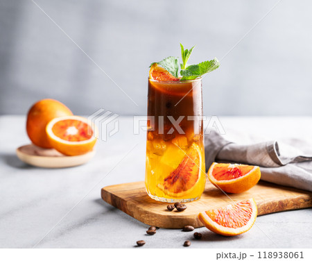 Coffee with orange juice (bumble) in a tall glass with ice and mint on a wooden board Coffee with orange juice (bumble) in a tall glass with ice and mint on a wooden board 118938061