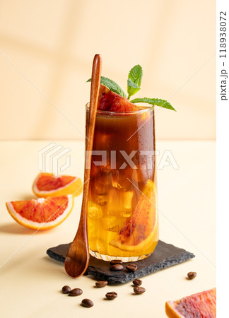 Espresso coffee with orange juice (bumble) in a tall glass with ice and mint on a yellow background 118938072
