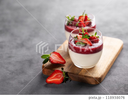 Strawberry and cream panna cotta in glasses with fresh berries on a wooden board on gray background. Strawberry and cream panna cotta in glasses with fresh berries on a wooden board on gray background. 118938076