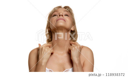 Portrait of beautiful woman, middle-aged lady doing massage for neck against white studio background. Toned neckline. 118938372