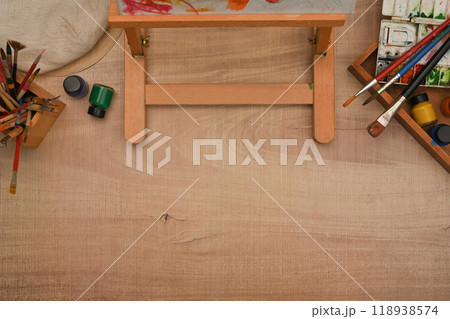 Variety of art supplies and easel on wooden background for a painting session 118938574