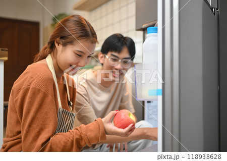 Young couple picking up some fruit from the fridge to making healthy breakfast Young couple picking up some fruit from the fridge to making healthy breakfast 118938628