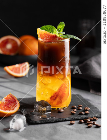 Coffee with orange juice (bumble) in a tall glass with ice and mint on a dark background  118938677