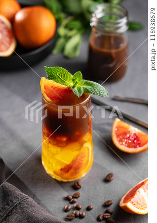 Coffee with orange juice (bumble) in a tall glass with ice and mint on a dark background 118938679