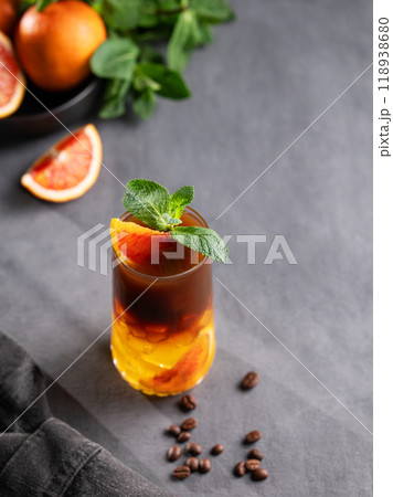Coffee with orange juice (bumble) in a tall glass with ice and mint on a dark background 118938680