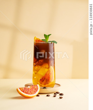 Americano coffee with orange juice (bumble) in a tall glass with ice and mint on a yellow background 118938681