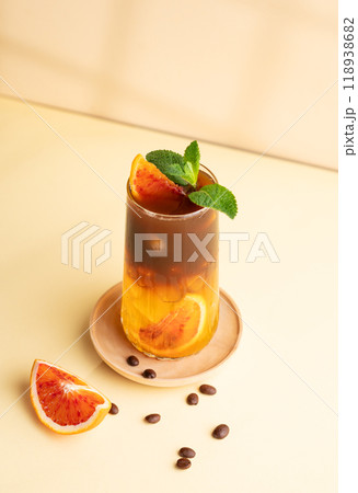 Americano coffee with orange juice (bumble) in a tall glass with ice and mint on a yellow background 118938682