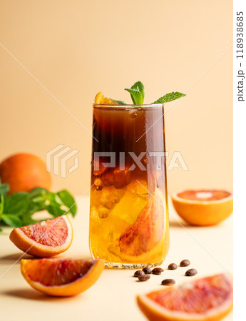 Americano coffee with orange juice (bumble) in a tall glass with ice and mint on a yellow background Americano coffee with orange juice (bumble) in a tall glass with ice and mint on a yellow background 118938685