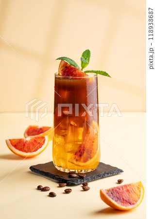 Espresso coffee with orange juice (bumble) in a tall glass with ice and mint on a yellow background 118938687