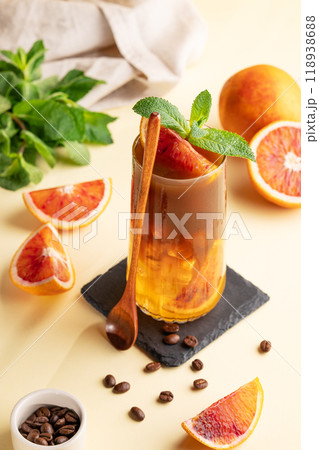 Espresso coffee with orange juice (bumble) in a tall glass with ice and mint on a yellow background 118938688