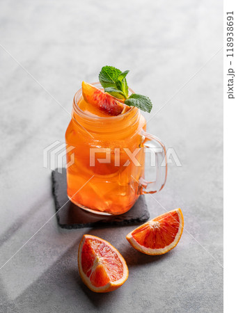 Freshly squeezed blood orange juice with ice, mint and a slice of fruit in a jar on blue background 118938691