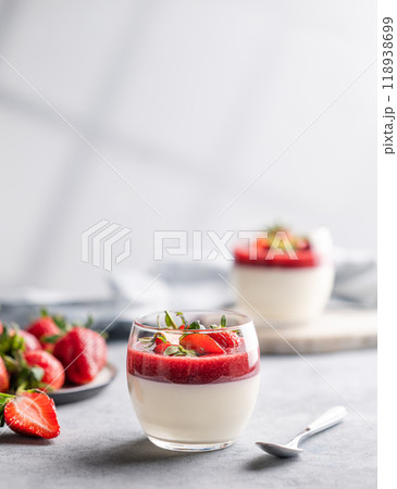 Panna cotta with strawberry and cream in glasses with berries on a light background with shadow. Panna cotta with strawberry and cream in glasses with berries on a light background with shadow. 118938699
