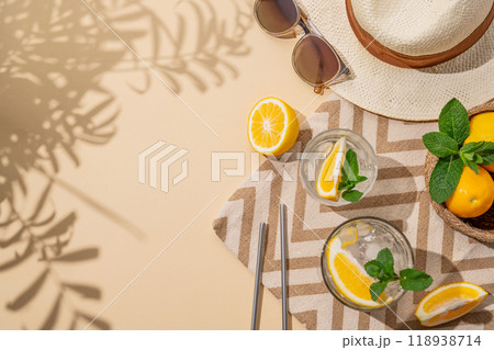 Summer layout with lemonade, citrus fruits, hat, beach towel and sunglasses on a beige background Summer layout with lemonade, citrus fruits, hat, beach towel and sunglasses on a beige background 118938714