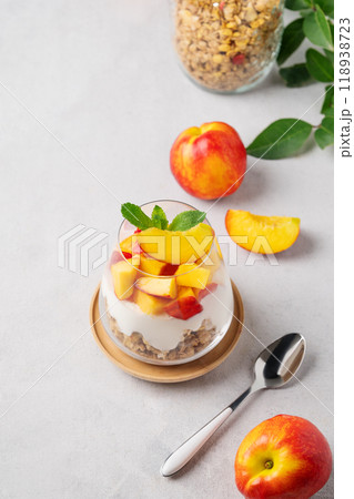 Flat lay of greek yogurt parfait with peach and muesli in a glass on a light background Flat lay of greek yogurt parfait with peach and muesli in a glass on a light background 118938723