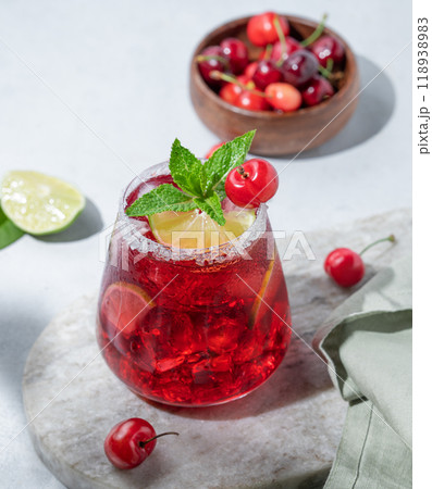 Cherry-lime mojito cocktail with mint, lime and ice on a marble board on a light background Cherry-lime mojito cocktail with mint, lime and ice on a marble board on a light background 118938983
