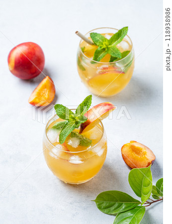 Two glasses with refreshing peach cocktail, lemonade or iced tea on a light background. 118938986