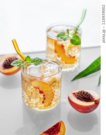 Homemade peach lemonade with ice and mint on white background. Fresh iced tea in glasses Homemade peach lemonade with ice and mint on white background. Fresh iced tea in glasses 118939002