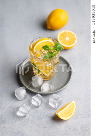 Iced tea with lemon, mint and ice in a glass on a light background with citrus fruits. 118939019