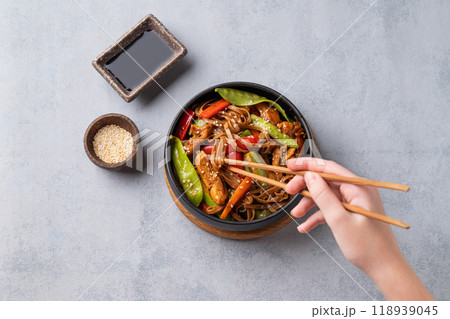 Stir-fry with soba noodles, meat and vegetables in black plate on a light background 118939045