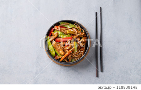 Stir-fry with soba noodles, meat and vegetables in black plate on a light background. 118939148