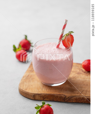 A glass of fresh strawberry smoothie on a wooden board on a light background with fresh berries. A glass of fresh strawberry smoothie on a wooden board on a light background with fresh berries. 118939185