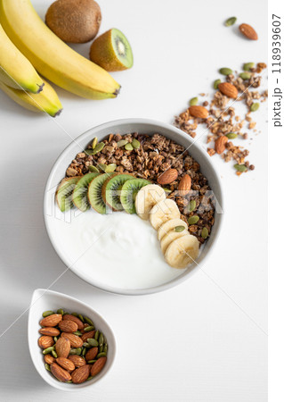 Granola and milk product with banana and kiwi on a white table. 118939607
