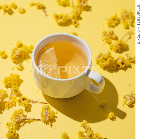 Herbal tea with immortelle and lemon in a white cup on a yellow background close up. Herbal tea with immortelle and lemon in a white cup on a yellow background close up. 118939618