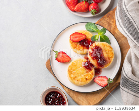 Cottage cheese, cheesecakes or syrniki sprinkled with berry sauce on a cutting board Cottage cheese, cheesecakes or syrniki sprinkled with berry sauce on a cutting board 118939634