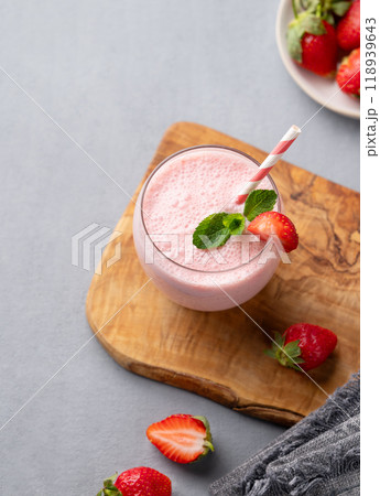 A glass of fresh strawberry smoothie with mint on a wooden board on a blue background A glass of fresh strawberry smoothie with mint on a wooden board on a blue background 118939643