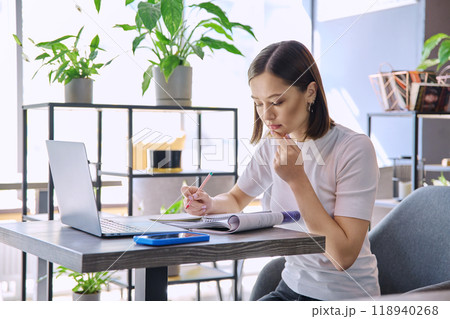 Female college student studying using laptop, sitting in coworking cafe Female college student studying using laptop, sitting in coworking cafe 118940268