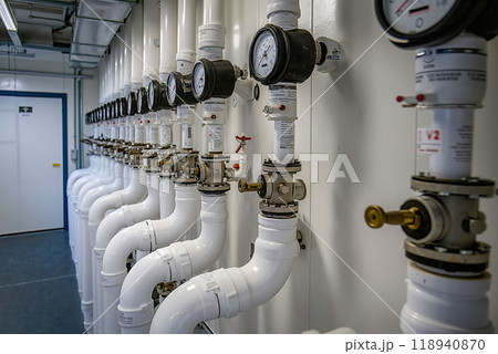 A row of pipes and gauges in a room with a door 118940870