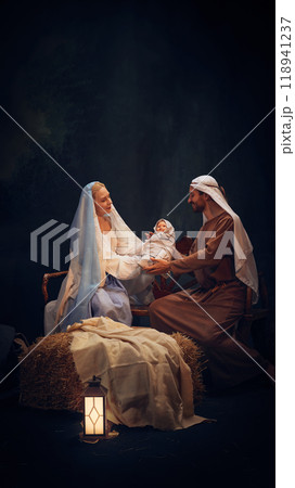 Holy and magical nativity scene with Mary gently holding baby Jesus with wise man, Joseph and shepherd standing around 118941237