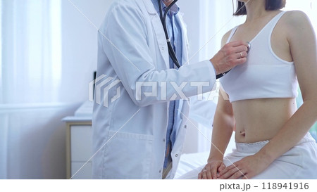 Doctor and patient. Physician is using stethoscope examining woman lungs in clinic cabinet. Medicine and health care Doctor and patient. Physician is using stethoscope examining woman lungs in clinic cabinet. Medicine and health care 118941916