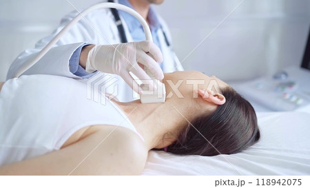 Doctor man is using ultrasound equipment on neck of female patient lying down for a medical examination. Medicine and science 118942075
