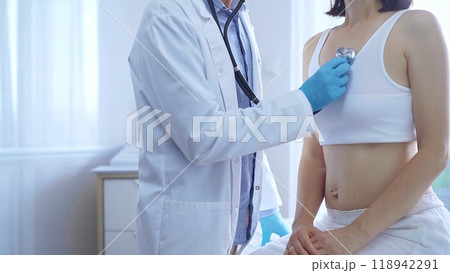 Doctor and patient. Physician wearing blue medical gloves is using stethoscope examining woman lungs in clinic. Medicine concept Doctor and patient. Physician wearing blue medical gloves is using stethoscope examining woman lungs in clinic. Medicine concept 118942291