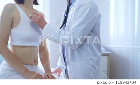 Doctor and patient. Physician is using stethoscope examining woman lungs in clinic cabinet. Medicine and health care 118942434
