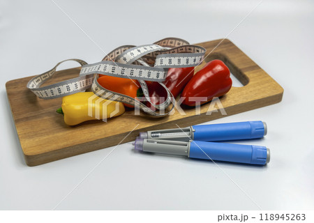 Ozempic Insulin injection pen for diabetics and weight loss and a cutting board with vegetables and a measuring tape. 118945263