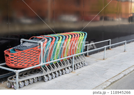 A row of empty colorful shopping carts near the supermarket. Consumer concept. A row of empty colorful shopping carts near the supermarket. Consumer concept. 118945266