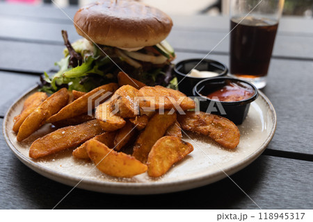Plate with burger and french fries, ketchup and mayonnaise and cola on the table. 118945317