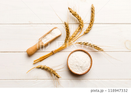Flat lay of Wheat flour in wooden bowl with wheat spikelets on colored background. world wheat crisis 118947332