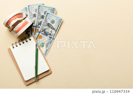 Flat lay composition with educational dental typodont model and money with notebook on colored table, top view. Expensive treatment Flat lay composition with educational dental typodont model and money with notebook on colored table, top view. Expensive treatment 118947334